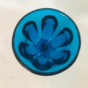 May include: A blue glass goblet with a flower design. The goblet is clear and has a textured surface.