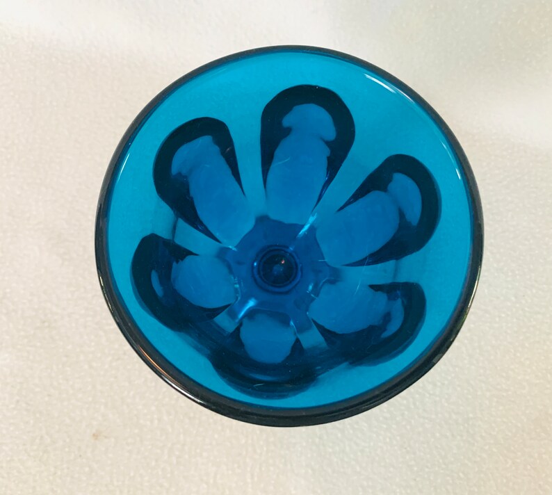 May include: A blue glass goblet with a flower design. The goblet is clear and has a textured surface.