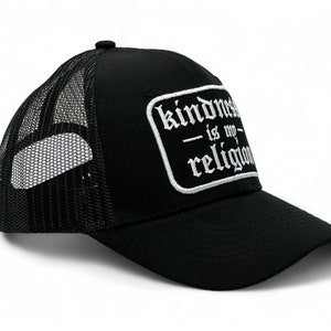 Könnte beinhalten: Schwarze Trucker-Kappe mit einem weißen gestickten Aufnäher, auf dem "Freundlichkeit ist meine Religion" steht.