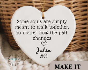 May include: White heart-shaped ornament with gold string for hanging. The ornament has the text "Some souls are simply meant to walk together, no matter how the path changes" and the name "Julia" with the year "2025".