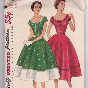 May include: Vintage Simplicity sewing pattern for a dress, size 12, bust 30. The pattern shows two women wearing dresses, one in green with white polka dots and a white petticoat, and the other in red with a black trim. The pattern is printed on a white paper background.