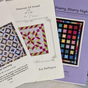 May include: Four quilting pattern books are displayed, showcasing various designs. The covers feature colorful quilt patterns, including geometric shapes and star motifs. Titles include "Designs to Share with You," "Diamonds All Around," "Starry, Starry Night," and "The Stitch Connection."