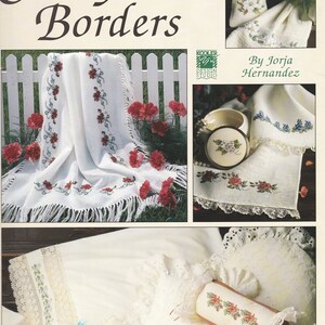 May include: A book titled "State Flower Borders" with cross stitch patterns for various floral designs. The book cover features images of embroidered items, including a pillow, a bag, and a small box.