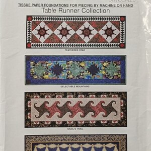 May include: A sewing pattern for a table runner collection featuring four designs: Feathered Star, Delectable Mountains, Snail's Trail, and Pineapple. The pattern is titled "Easy Big Blocks" by McCall's and has the number B523.