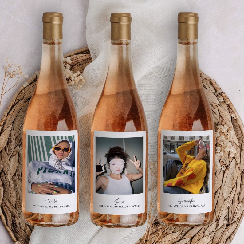 Op de afbeelding: Drie flessen ros&eacute; wijn met gepersonaliseerde etiketten met foto's van mensen en de tekst "Wil je mijn bruidsmeisje zijn?" of "Wil je mijn getuige zijn?"