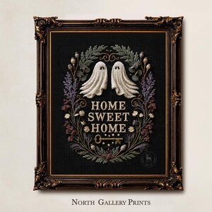 May include: A framed embroidery art piece on black fabric featuring two white ghosts, a floral wreath, and the text HOME SWEET HOME above a key. The ornate dark brown frame has gold accents. The text NORTH GALLERY PRINTS appears below the frame.