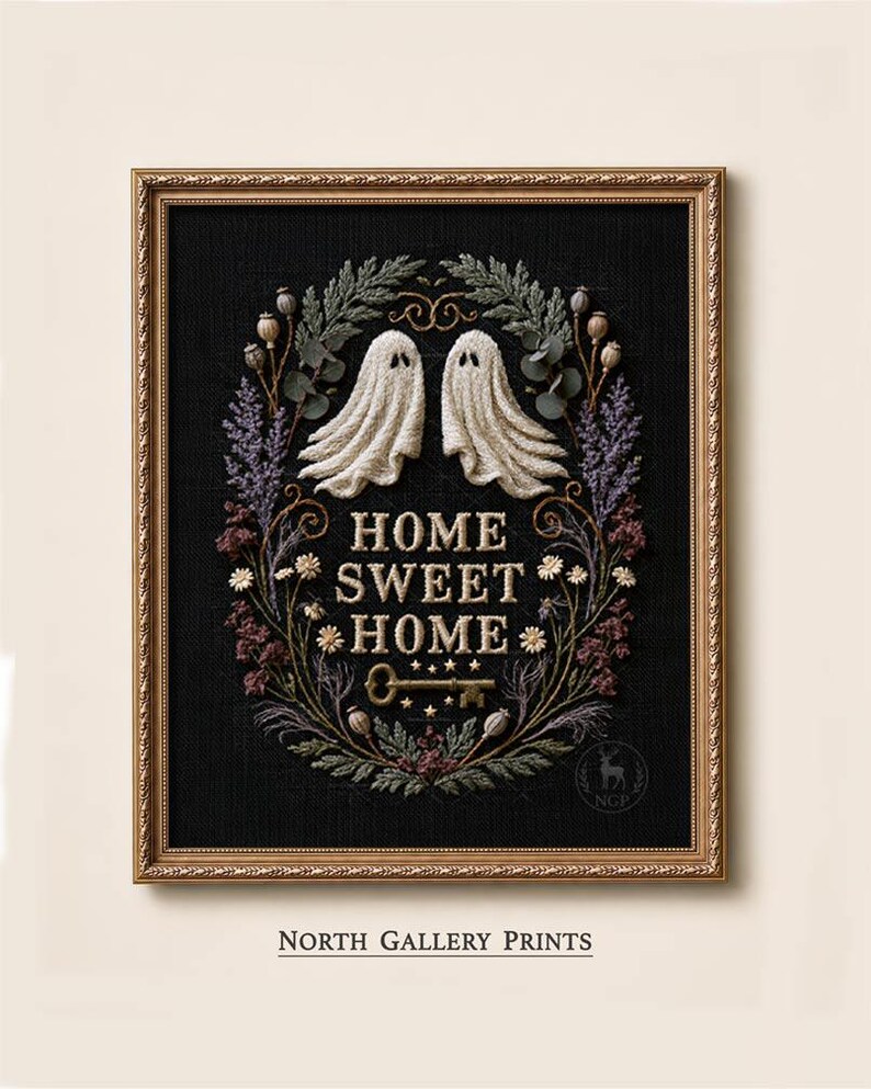 May include: A framed embroidery art piece on black fabric featuring two white ghosts, a central gold key, and the text "HOME SWEET HOME" surrounded by a wreath of dried flowers, seed pods, and greenery in muted tones of purple, green, and brown.