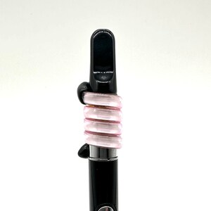 May include: A black and pink glass vape pen with a mouthpiece and a coil.