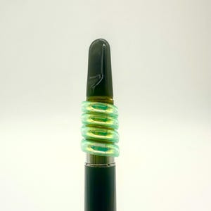 May include: A black and green vape pen with a black mouthpiece and a green silicone sleeve.