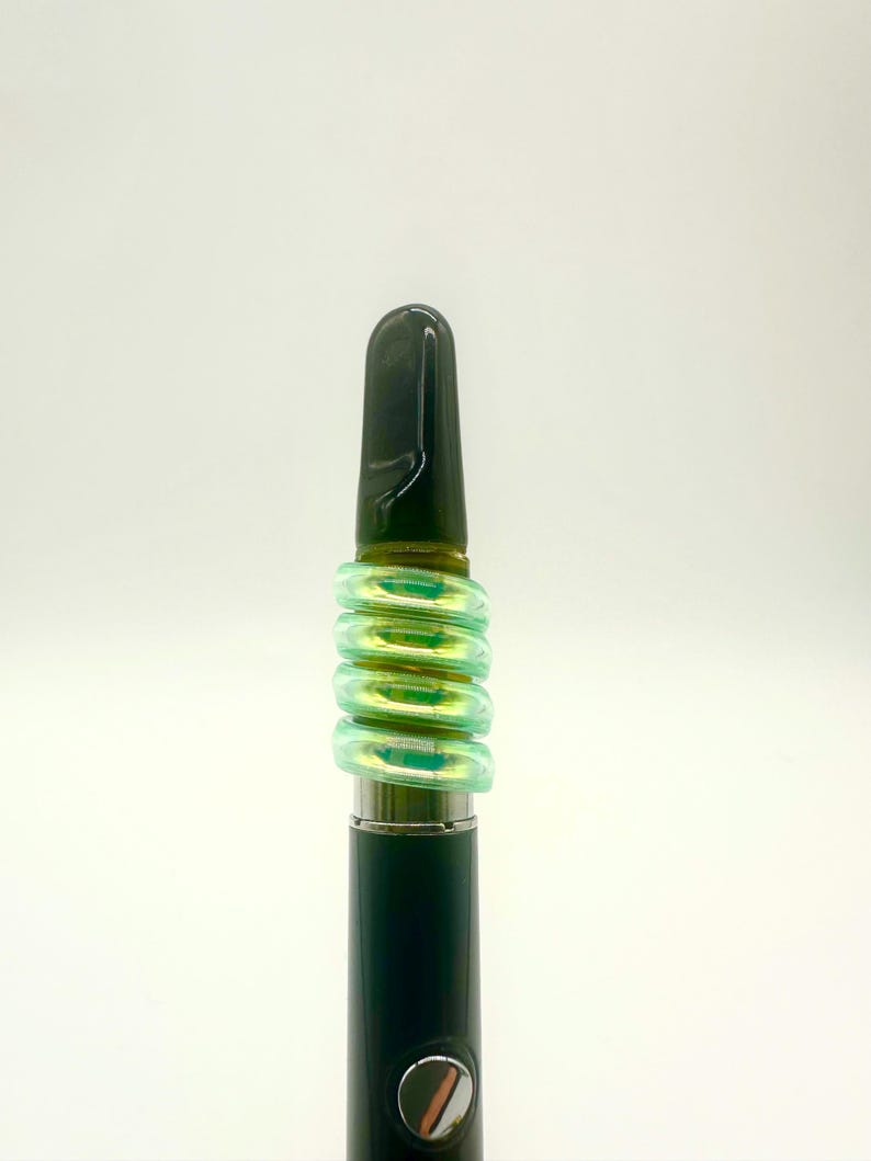 May include: A black and green vape pen with a black mouthpiece and a green silicone sleeve.