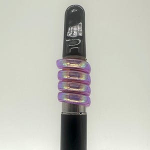 May include: A black vape pen with a purple iridescent glass mouthpiece. The mouthpiece is made of several rings that are stacked on top of each other.