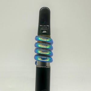 May include: A black and silver vape pen with a blue iridescent glass mouthpiece. The mouthpiece is made of multiple rings that are stacked on top of each other.