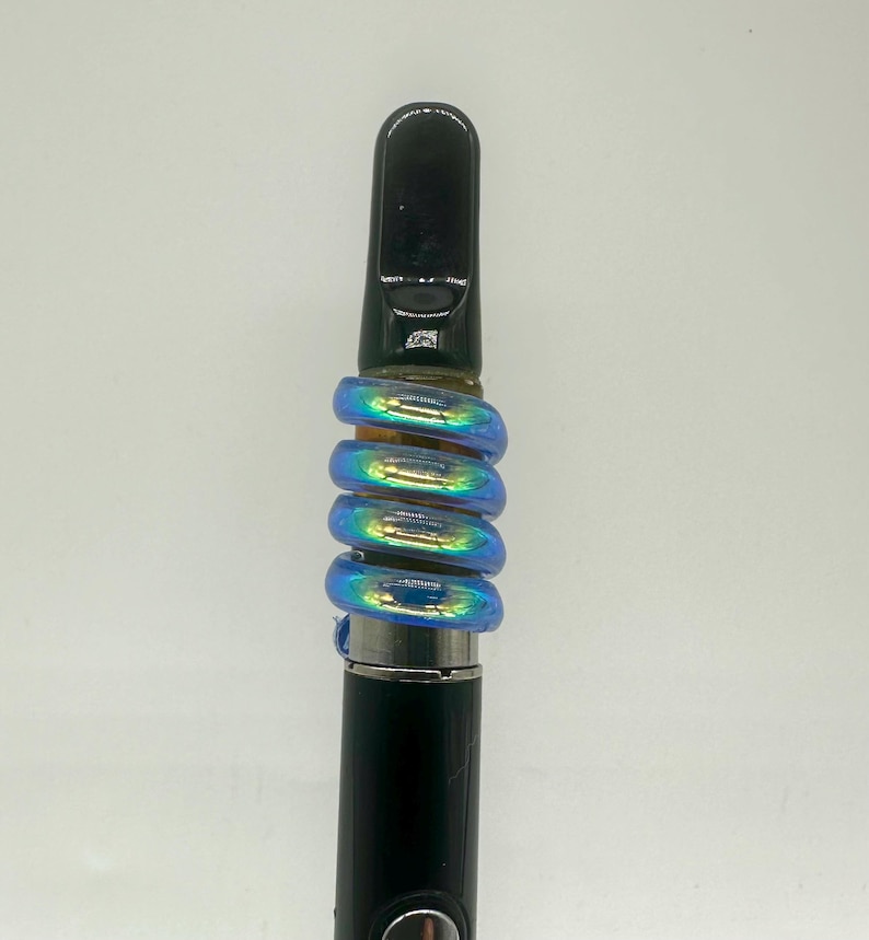May include: A black and silver vape pen with a blue iridescent glass mouthpiece. The mouthpiece is made of multiple rings that are stacked on top of each other.