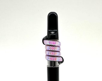 May include: A black vape pen with a pink and white iridescent patterned silicone sleeve.