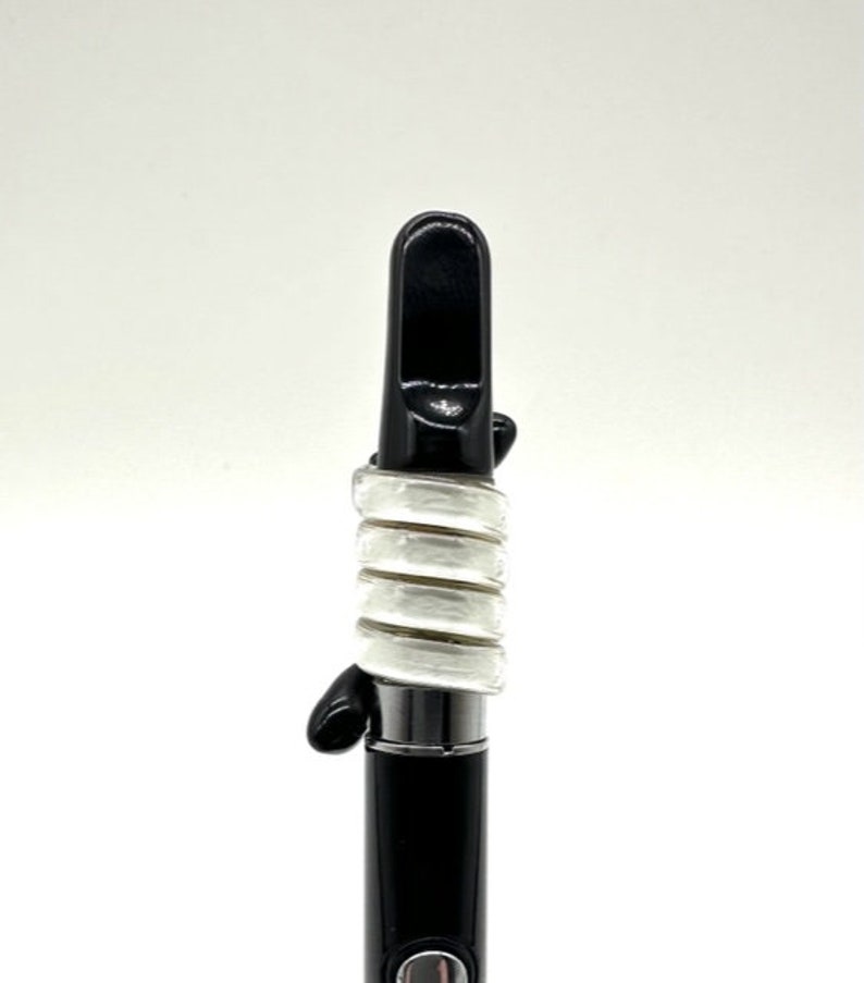 May include: A black and white vape pen with a mouthpiece and a white silicone sleeve.