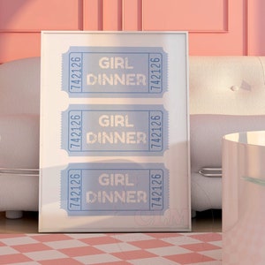 May include: A framed print featuring three blue tickets, each displaying the text "Girl Dinner" and the number "7421226". The print is hung on a pink wall above a white sofa and a pink and white chequered rug.