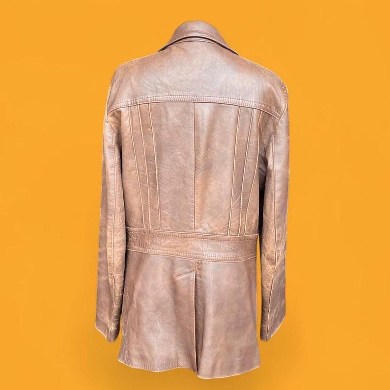 May include: A brown leather jacket shown from the back, featuring a structured collar, vertical seam detailing across the upper back, and a horizontal waistband panel. The garment has long sleeves and a straight hemline with a central back vent.