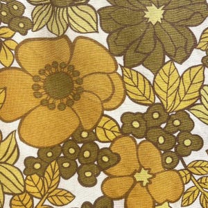 May include: A textile fabric featuring a repeating floral pattern in shades of mustard yellow, olive green, and dark brown on a white background. The design consists of large stylized flowers, smaller clusters of round blossoms, and pointed leaves.