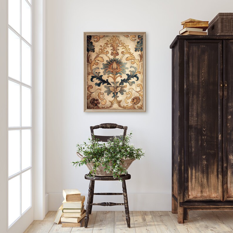 May include: A framed print of a vintage floral pattern in shades of blue, gold, and brown. The print is hanging on a white wall above a wooden chair with a potted plant.