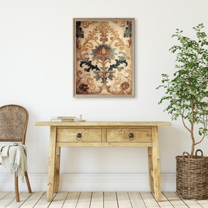 May include: A framed print of a vintage floral pattern in shades of brown, gold, and blue. The print is hanging on a white wall above a wooden console table.