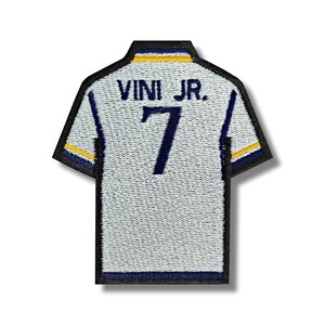 May include: White soccer jersey patch with blue and yellow trim. The back of the jersey has the text "VINI JR." and the number "7" in blue.