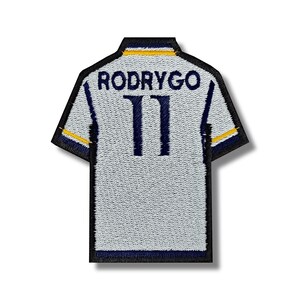 Può includere: Maglia da calcio bianca con bordini blu e gialli. Sul retro della maglia è presente il nome "RODRYGO" e il numero "11" in blu.