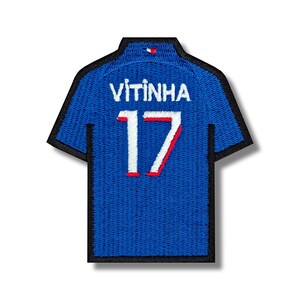 Pode incluir: Etiqueta de camisola de futebol azul com costuras brancas e vermelhas. A camisola tem o nome "Vitinha" e o número "17" nas costas.