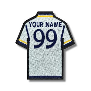 May include: White and blue embroidered iron-on patch shaped like a soccer jersey with the text "YOUR NAME" and the number "99" on the back.