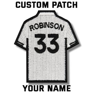 Peut inclure: Un écusson personnalisé en forme de maillot avec le nom "ROBINSON" et le numéro "33" en noir sur fond blanc. L'écusson comprend également le texte "CUSTOM PATCH" et "YOUR NAME" en noir.