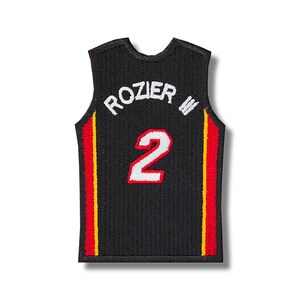 Peut inclure: Maillot de basket noir avec des bandes rouges et jaunes sur les côtés. Le maillot porte le nom "ROZIER" et le numéro "2" au dos.