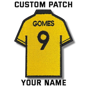 以下が含まれることがあります： 黒い持ち手と「But First, Coffee」のテキストが黒い太字で書かれた白いセラミックマグ。マグカップはぼやけた背景に置かれており、居心地の良い環境を連想させます。