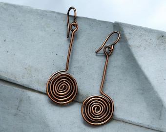 May include: A pair of copper wire earrings with a spiral design. The earrings are long and dangle, with a hook closure.