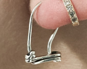 May include: A silver hoop earring with a twisted knot design. The earring is worn in the earlobe.