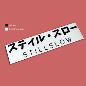 Può includere: Adesivo bianco con testo nero che dice "スティル・スロー STILL SLOW".