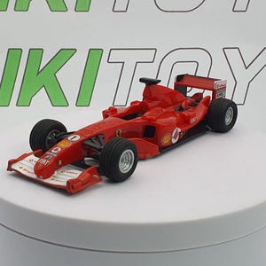 May include: A red and black toy Formula 1 race car with the number "1" on the side. The car is on a white display stand.