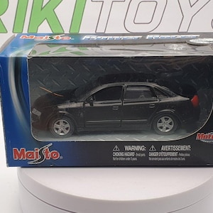 May include: A black Maisto model car in its original packaging. The toy car is a sedan with silver wheels and red taillights. The packaging is blue and black with the Maisto logo and the text "Motorized".