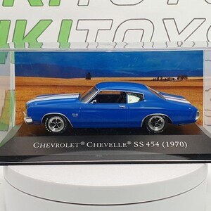 Może przedstawiać: Niebieski model samochodu Chevrolet Chevelle SS 454 z 1970 roku w przezroczystej gablocie. Samochód stoi na czarnej podstawie z napisem "CHEVROLET CHEVELLE SS 454 (1970)".