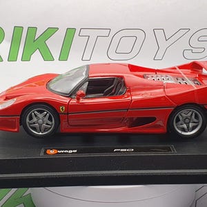 May include: A red 1:18 scale model of a Ferrari F50 sports car on a black display base. The model features a detailed interior and exterior, including the iconic Ferrari logo on the side.