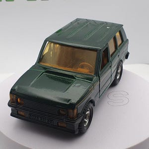 May include: A dark green toy car model of a Range Rover. The car has a detailed exterior and a black grille.