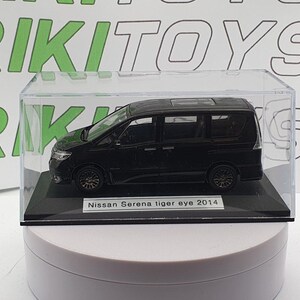 Op de afbeelding: Zwarte Nissan Serena Tiger Eye 2014 modellauto in een transparante vitrine op een witte basis. De auto is een model op schaal 1:18.