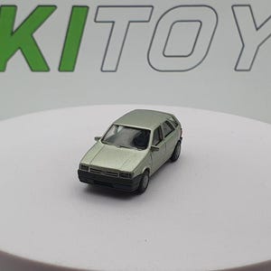 May include: A light green toy car model of a Fiat Uno, a compact hatchback car. The car is on a white surface.