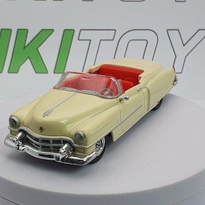 Peut inclure: Une voiture jouet décapotable de couleur crème avec un intérieur rouge. La voiture présente des détails chromés sur le pare-chocs avant et les phares. Ce modèle de voiture jouet classique date probablement du milieu du XXe siècle.
