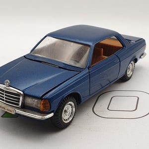 May include: A blue diecast model car of a Mercedes-Benz 240D, a classic sedan with a black grille and chrome accents. The car is in excellent condition and has a detailed interior.