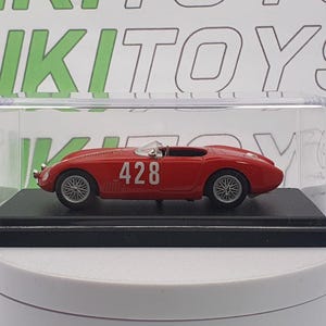 May include: A red toy race car with the number 428 on the side, displayed in a clear plastic case. The miniature car has silver wheels and a white windshield. The car sits on a black base.