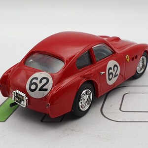 May include: A red toy car with a white number 62 on each side. The car has a black interior and a black windscreen. The car is a model of a classic sports car.