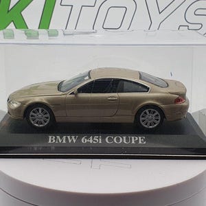 Może przedstawiać: Model samochodu w skali 1:18 wykonany z odlewu ciśnieniowego, przedstawiający BMW 645i Coupe, umieszczony w przezroczystej gablocie. Samochód ma czarne koła i czarne wnętrze.