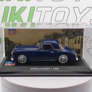 Puede incluir: Un coche modelo azul Simca 8 Sport de 1952 en una vitrina transparente. El coche es un modelo a escala 1/18 y tiene un interior y un exterior detallados.