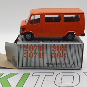 May include: Orange toy van with a white box. The box has the text "207 D 307 D 208 308 Mercedes-Benz" printed on it.