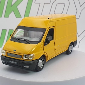 Può includere: Modello giocattolo di un furgone Ford Transit giallo. Il furgone in miniatura presenta dettagli neri, una griglia anteriore e una targa con la scritta "KTP 9801". Il giocattolo è ambientato su uno sfondo bianco con testo verde e grigio.