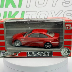 May include: A red die-cast model car in a clear plastic display case. The car is a coupe with silver wheels. The box has the text "EP ON ROAD" and "HEAVY METAL". The scale is 1:43.